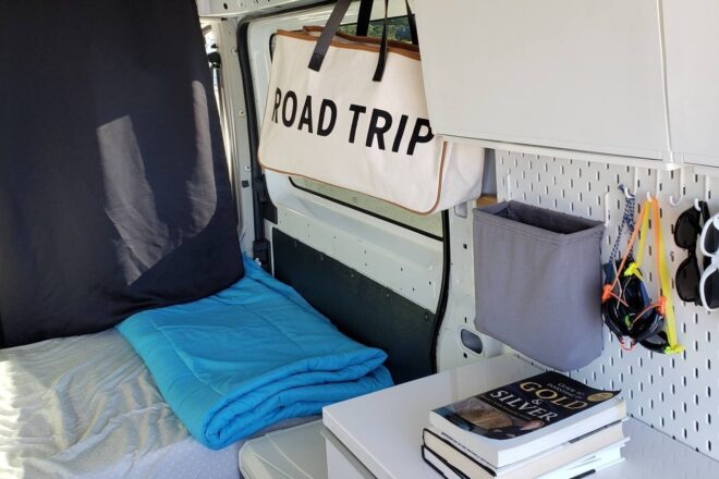 interior space of converted van, focusing on a corner of a desk and the bed