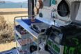 interior space of converted van, looking out on the ocean outside and showing a small kitchen compartment