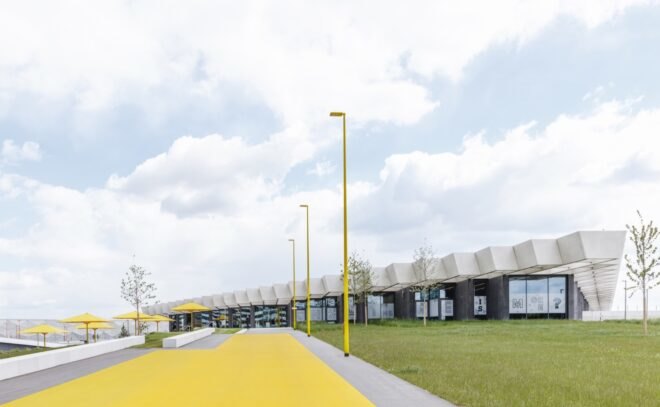 yellow track and umbrella-covered seating areas near glass building