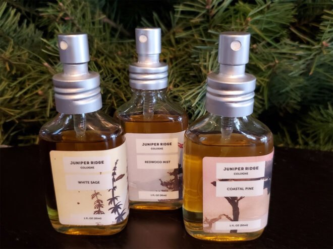 three cologne bottles in front of evergreen leaves