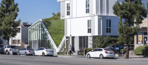 a close-up street view of the housing project, a large white building with a green space feature in the middle