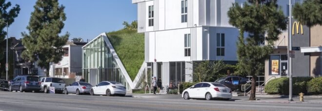 a close-up street view of the housing project, a large white building with a green space feature in the middle