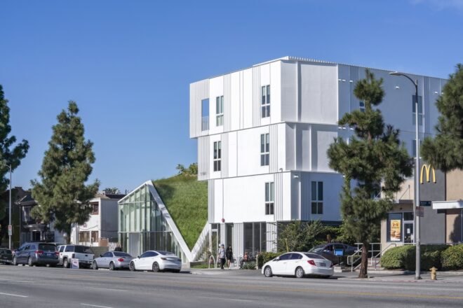 a street view of the housing project, a large white building with a green space feature in the middle