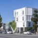 a street view of the housing project, a large white building with a green space feature in the middle