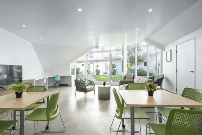interior of a lounge area with wood-top tables with green chairs