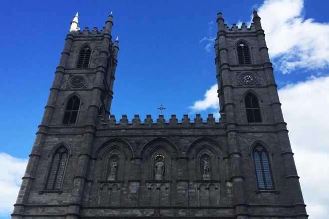 the exterior of Notre Dame Basilica, a gray stone structure with a blue shy overhead