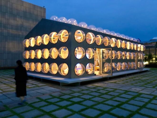 gabled building with bubble-like windows all lit up from within at night