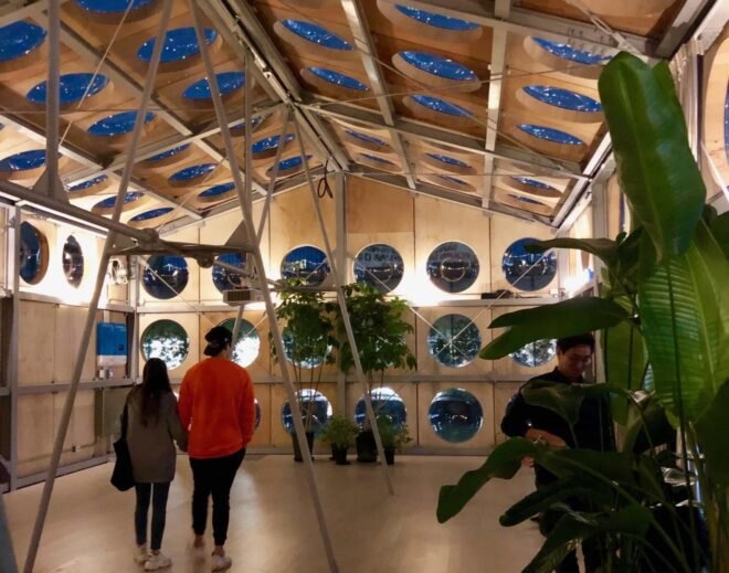 people inside wood-lined building with many round windows