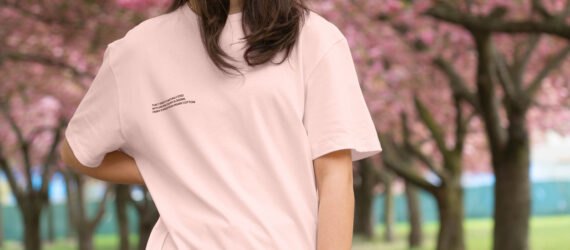person wearing pink T-shirt and standing in front of cherry blossom trees
