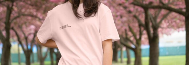 person wearing pink T-shirt and standing in front of cherry blossom trees