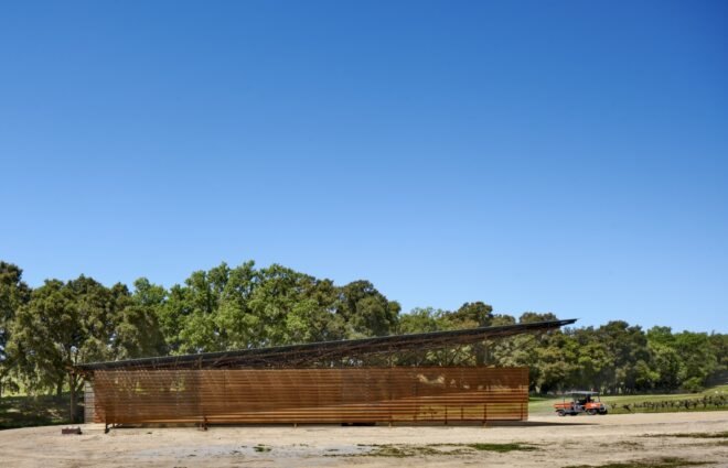 a wide shot of a barn with a tractor to the right and trees in the background.