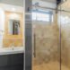 bathroom with tan-tiled shower stall