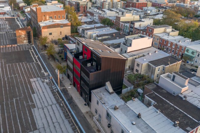 black, gray and red townhomes topped with solar panels in a city
