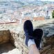 feet in blue sneakers propped up on rock with city views below