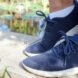 feet in blue sneakers standing on a ledge near a pond