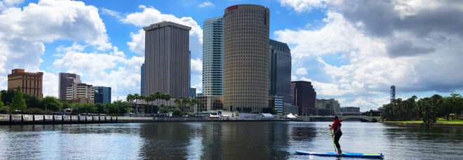 A city skyline view of Tampa with a river in the foreground