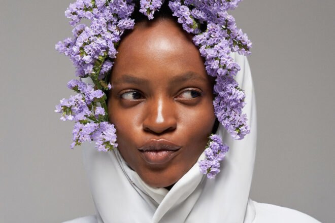 person with hood of puffer coat up and stuffed with purple flowers