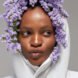 person with hood of puffer coat up and stuffed with purple flowers