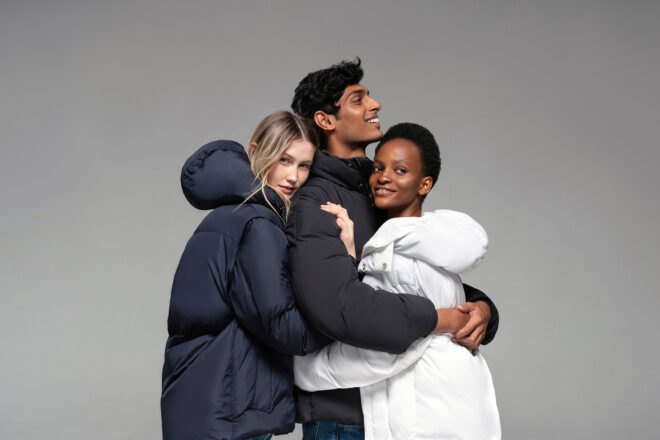 three people wearing puffer coats and hugging