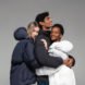 three people wearing puffer coats and hugging