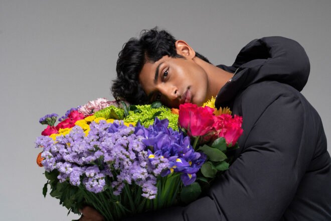 Person wearing puffer coat and smelling multicolored flower bouquet