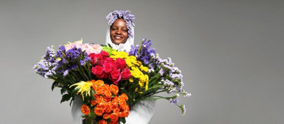 person in puffer jacket holding massive, multicolored bouquet of flowers