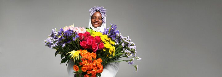 person in puffer jacket holding massive, multicolored bouquet of flowers