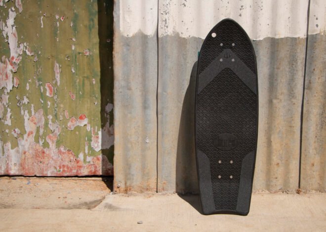 black skateboard leaning on a wall