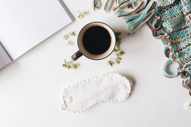 cotton sleep mask near cup of coffee and blanket