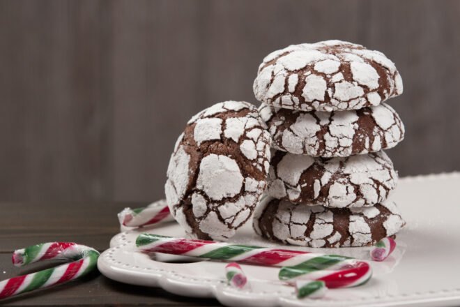 pile of chocolate crinkle cookies next to broken up candy canes
