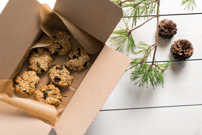 Aerial view of oatmeal raisin cookies in a box near evergreen tree branches