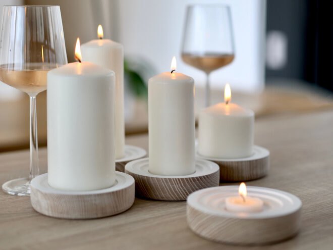 lit candles in wood holders near glasses of wine