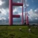 red wind turbines with extra parts on the side of the main pole