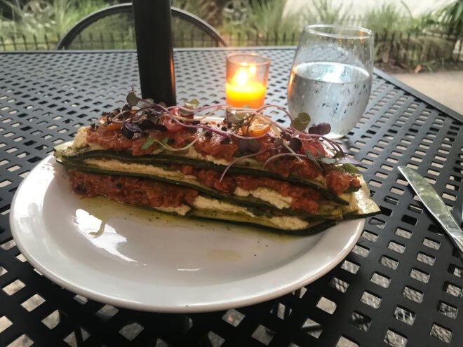 vegan lasagna on white plate near candle