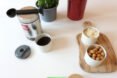 small white, round containers filled with snacks on a wood board