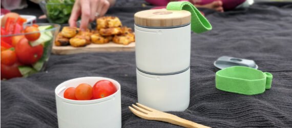 stacked white containers with snacks on a picnic blanket