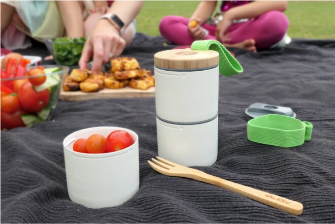 stacked white containers with snacks on a picnic blanket