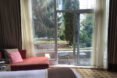 white bed in hotel room with glass wall leading to a balcony
