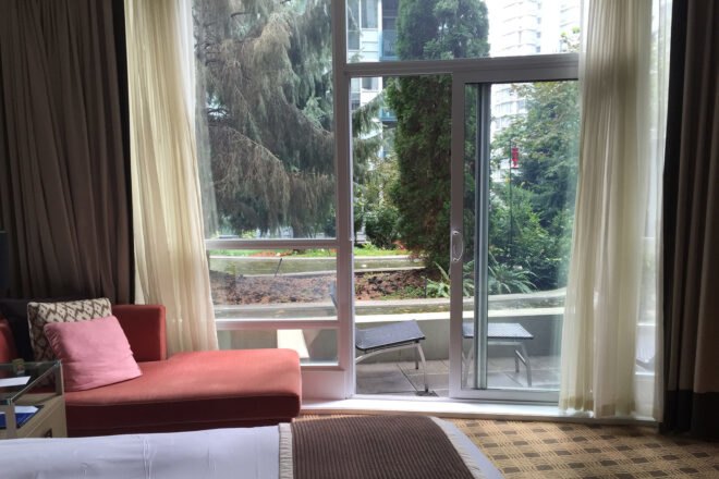 white bed in hotel room with glass wall leading to a balcony