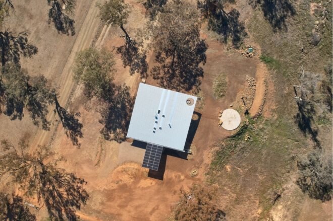 aerial shot of square home surrounded by dry fields
