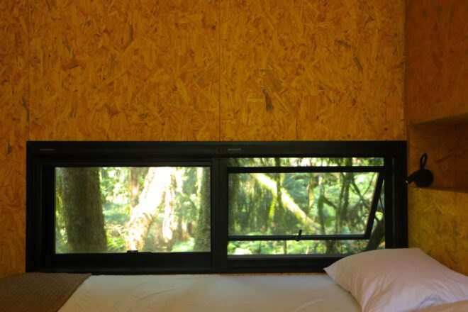 bed up against a wall with horizontal windows