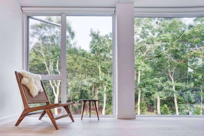 small wood chair beside glass wall