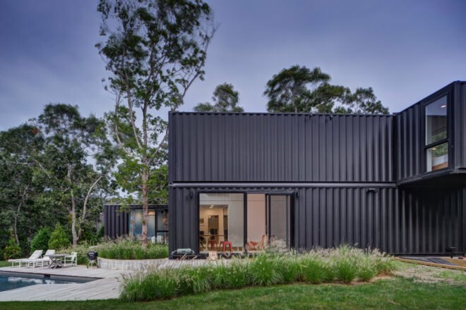 black shipping container home with sliding glass doors leading out to a patio