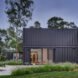 black shipping container home with sliding glass doors leading out to a patio