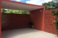 a red garage-like structure with dotted fence-like structure on either side of solid walls
