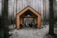 people huddled inside a gabled timber structure in a forest
