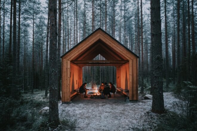 people around a fire pit inside a wood gabled structure
