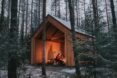 warm glow from a firepit inside a gabled wood structure in the woods
