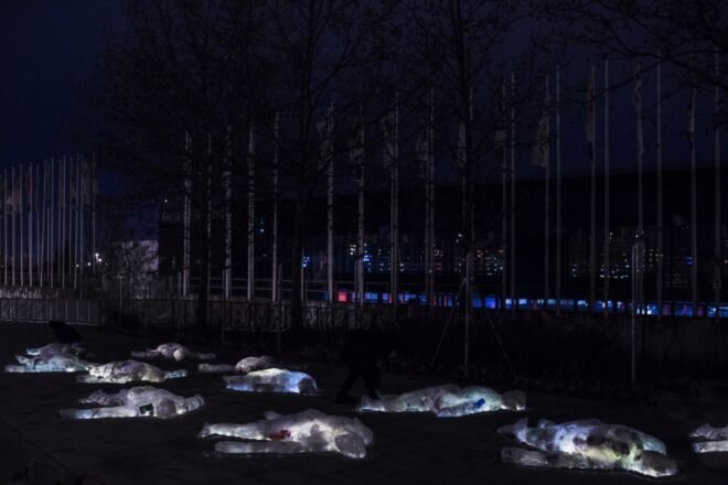 several body-shaped plastic sculptures outside at night