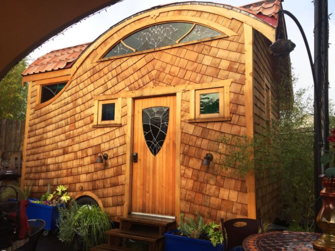 a tiny house with a wood facade and front door with decorative glass cut-out